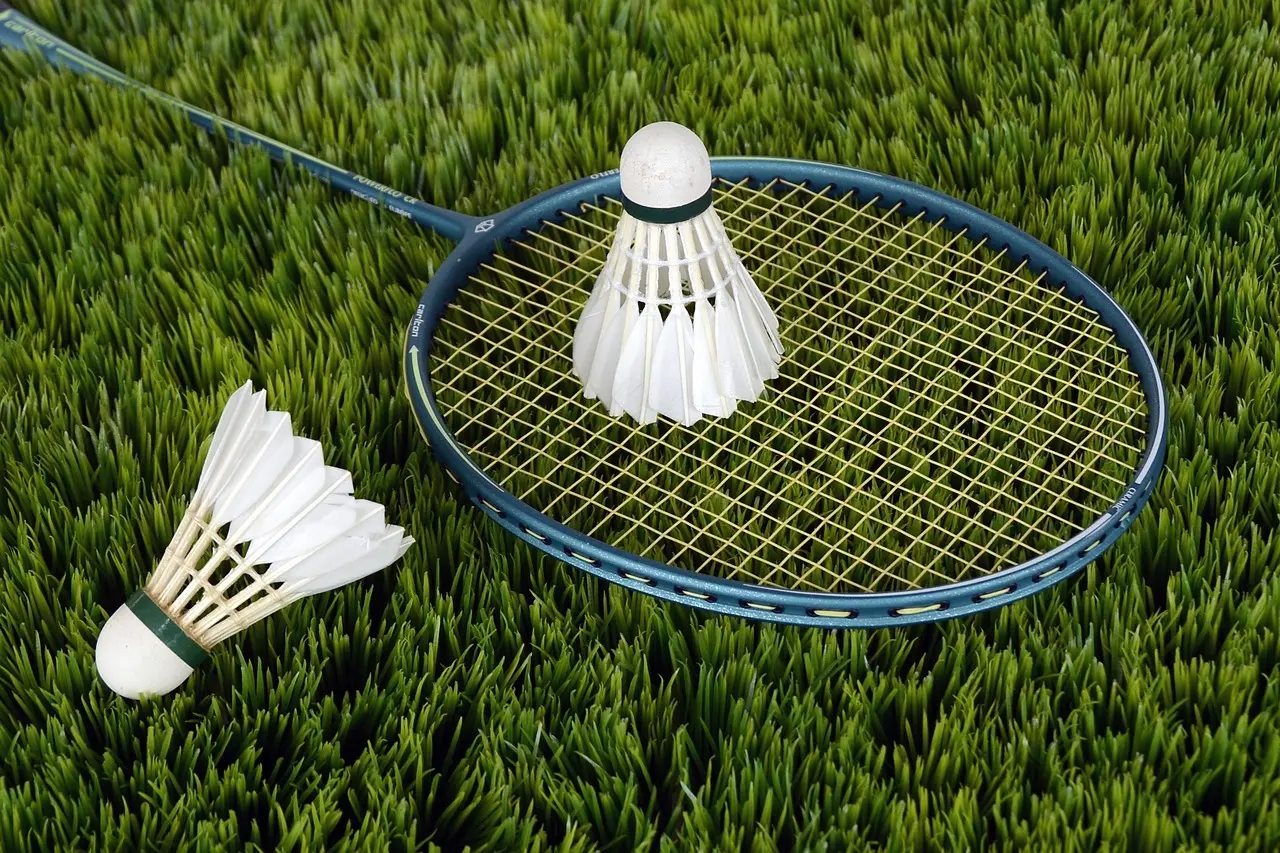 Badmintonketcher og to fjerbolde på græs